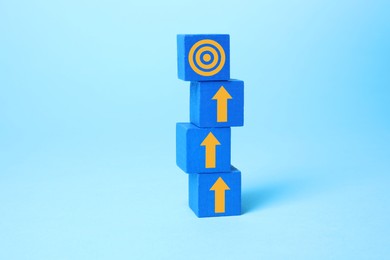 Image of Targeting. Stacked cubes with arrows pointing at bullseye on top cube against light blue background