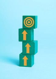 Image of Targeting. Stacked green cubes with arrows pointing at bullseye on top cube against light blue background