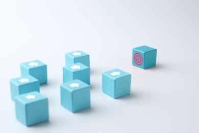 Image of Targeting. Light blue cubes with arrows pointing at one with bullseye on white background