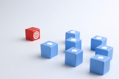 Image of Targeting. Light blue cubes with arrows pointing at red one with bullseye on white background