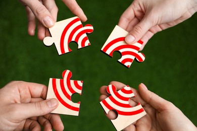 Image of Targeting. People putting puzzle pieces together to make image of bullseye over green grass, top view