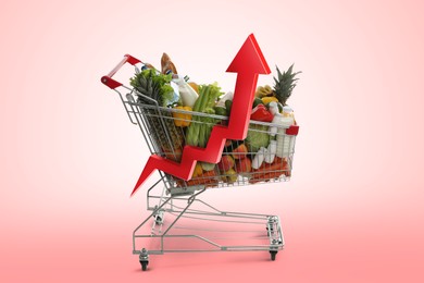 Image of Shopping cart with different groceries and upward red arrow against pink gradient background. Rising cost for food basket. Consumer Price Index