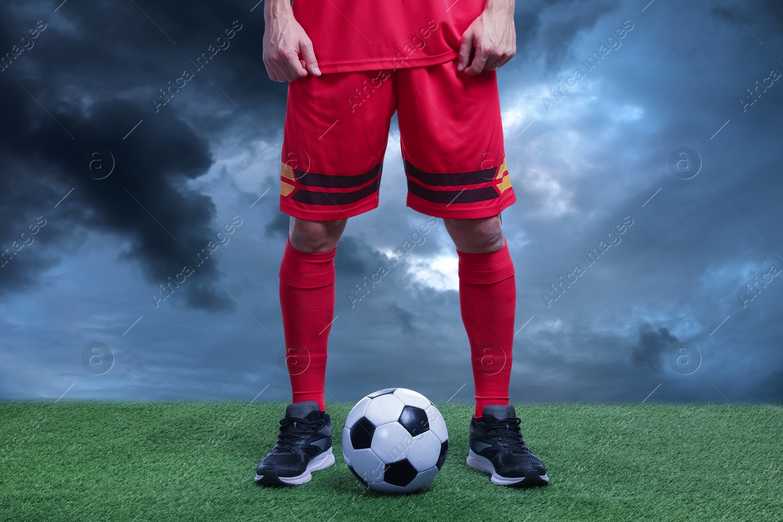 Football player with soccer ball under gloomy sky, closeup Image of Football player with soccer ball under gloomy sky, closeup