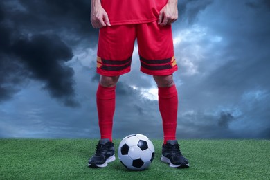 Image of Football player with soccer ball under gloomy sky, closeup