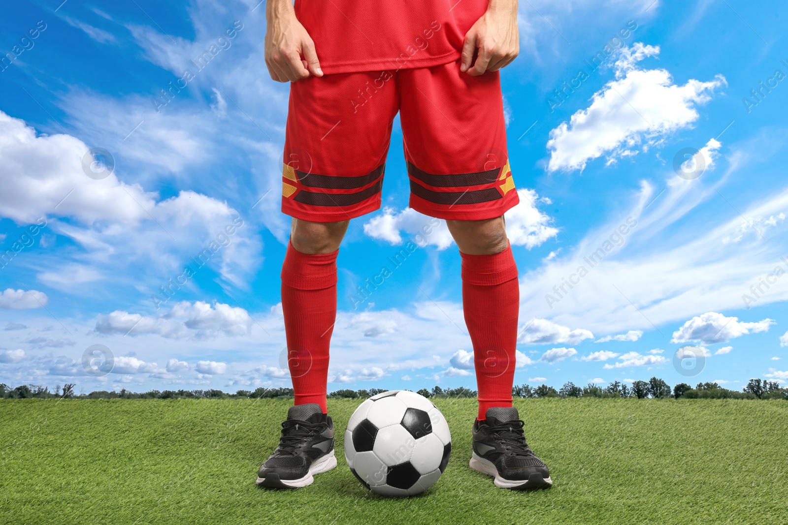 Football player with soccer ball under blue sky, closeup Image of Football player with soccer ball under blue sky, closeup