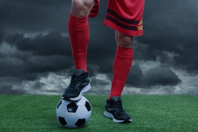 Image of Football player with soccer ball under gloomy sky, closeup