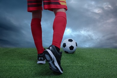 Image of Football player kicking soccer ball under gloomy sky, closeup