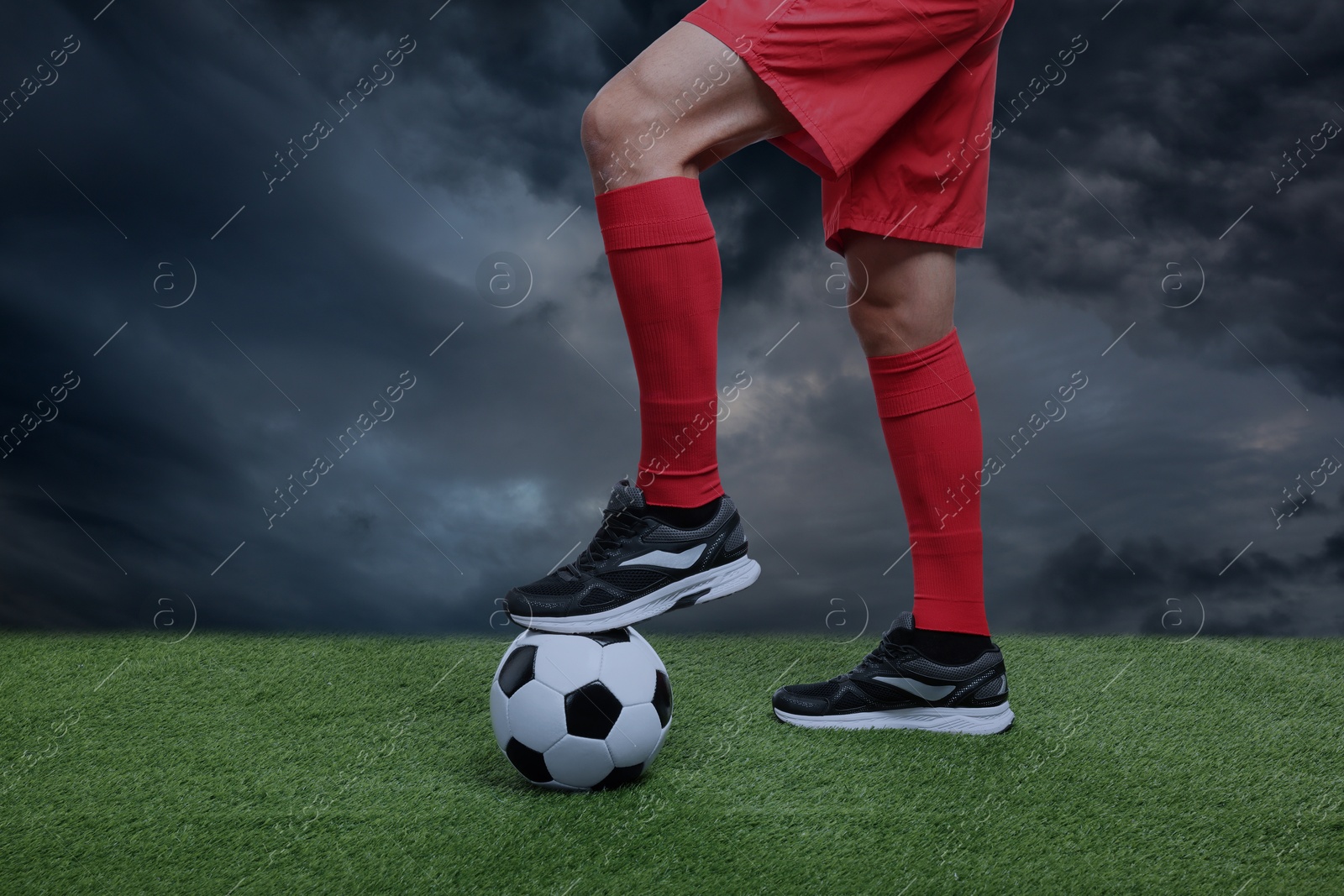 Football player with soccer ball under gloomy sky, closeup Image of Football player with soccer ball under gloomy sky, closeup