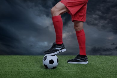 Image of Football player with soccer ball under gloomy sky, closeup