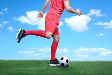 Image of Football player kicking soccer ball under blue sky, closeup