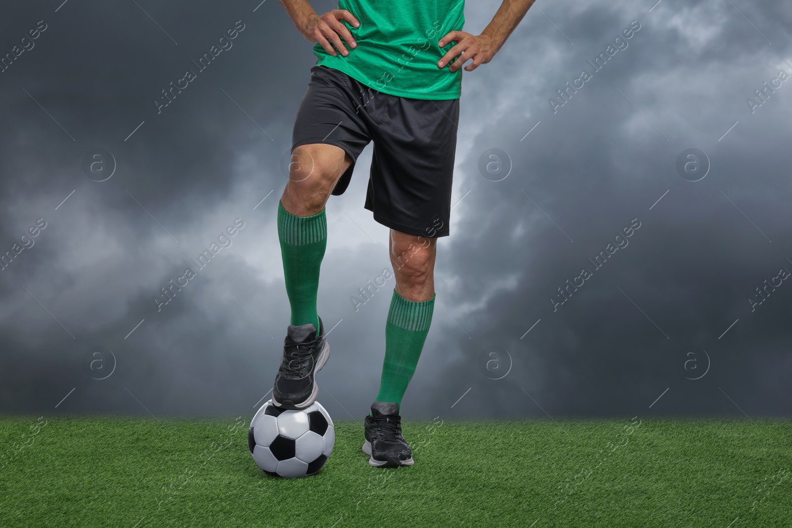 Football player with soccer ball under gloomy sky, closeup Image of Football player with soccer ball under gloomy sky, closeup