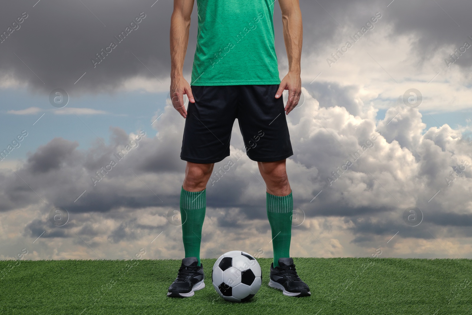 Football player with soccer ball against cloudy sky, closeup Image of Football player with soccer ball against cloudy sky, closeup