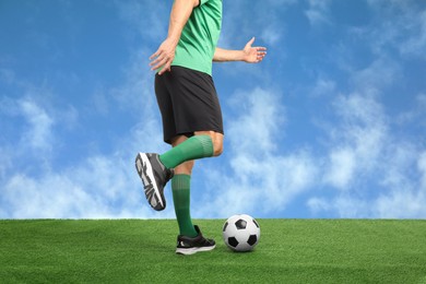 Image of Football player kicking soccer ball under blue sky, closeup