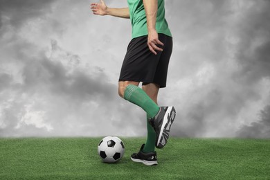 Image of Football player kicking soccer ball under cloudy sky, closeup