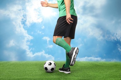 Image of Football player kicking soccer ball under blue sky, closeup