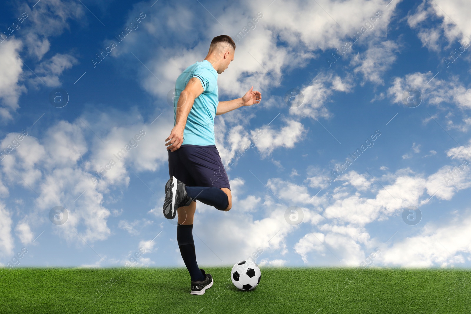 Football player kicking soccer ball under blue sky Image of Football player kicking soccer ball under blue sky