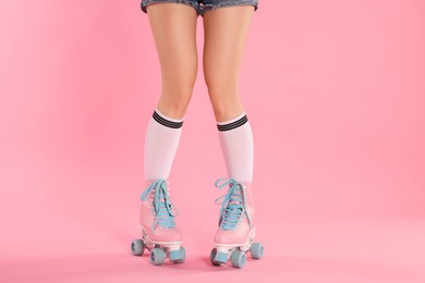 Photo of Woman in roller skates on pink background, closeup