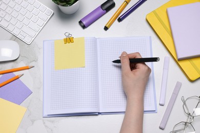 Photo of Woman with planner and stationery at light marble table, top view
