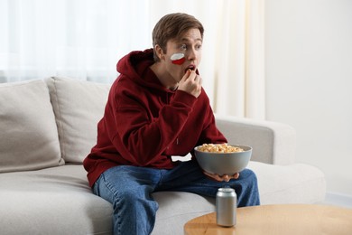 Photo of Sports fan eating popcorn while watching game indoors
