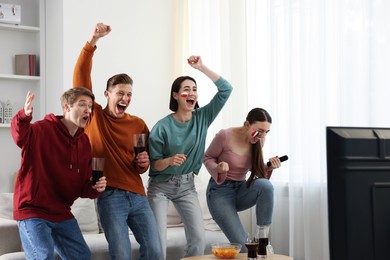 Photo of Emotional sports fans watching game together indoors