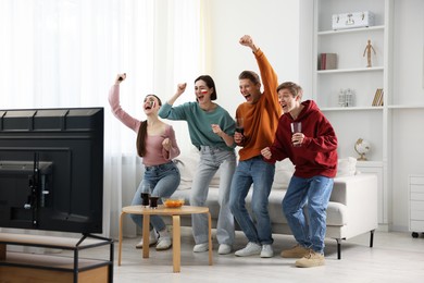 Photo of Emotional sports fans watching game together indoors