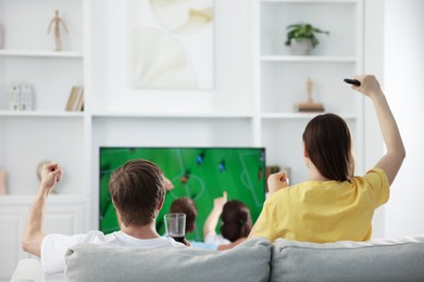 Photo of Group of football fans watching game together indoors, back view