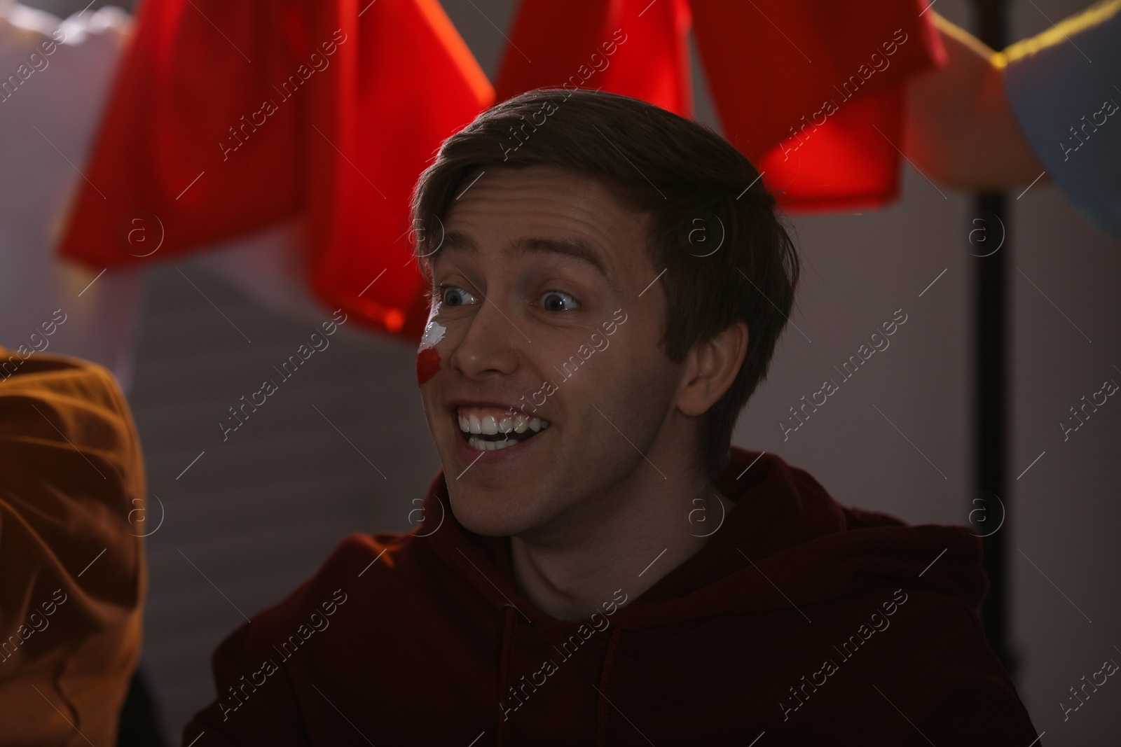 Emotional sports fan with drawing of Polish flag watching game indoors Photo of Emotional sports fan with drawing of Polish flag watching game indoors