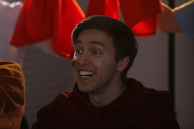 Photo of Emotional sports fan with drawing of Polish flag watching game indoors