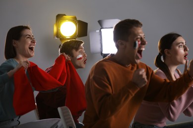 Photo of Emotional sports fans watching game together indoors