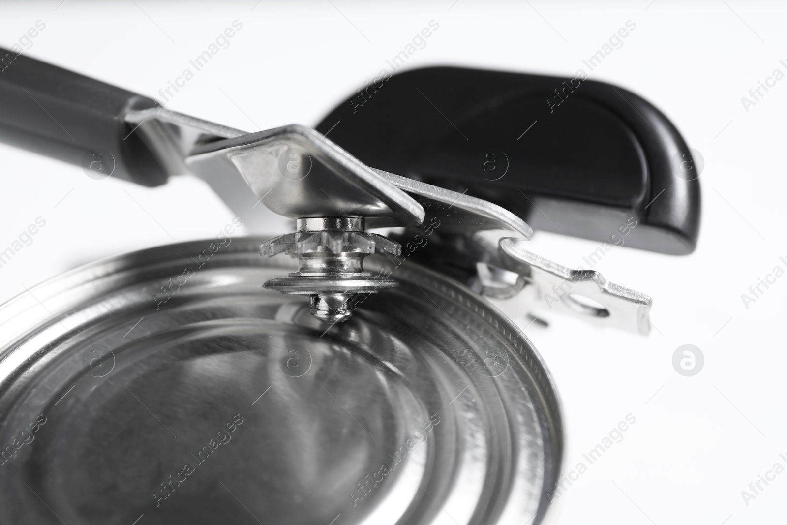 Can opener and tin on white table, closeup Photo of Can opener and tin on white table, closeup