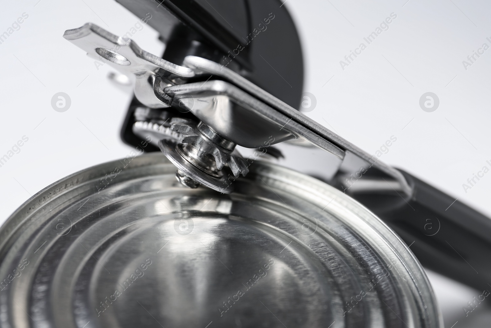 Can opener and tin on white table, closeup Photo of Can opener and tin on white table, closeup