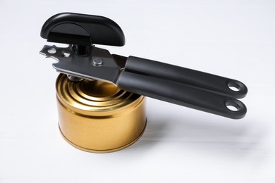 Photo of Can opener and tin on white wooden table