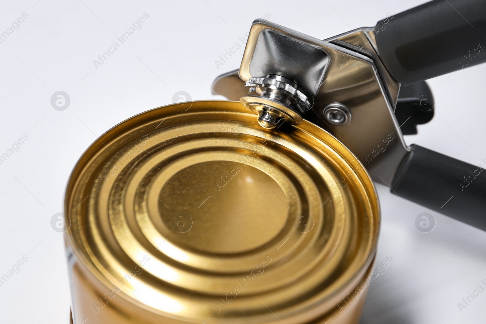 Can opener and tin on white table, closeup Photo of Can opener and tin on white table, closeup