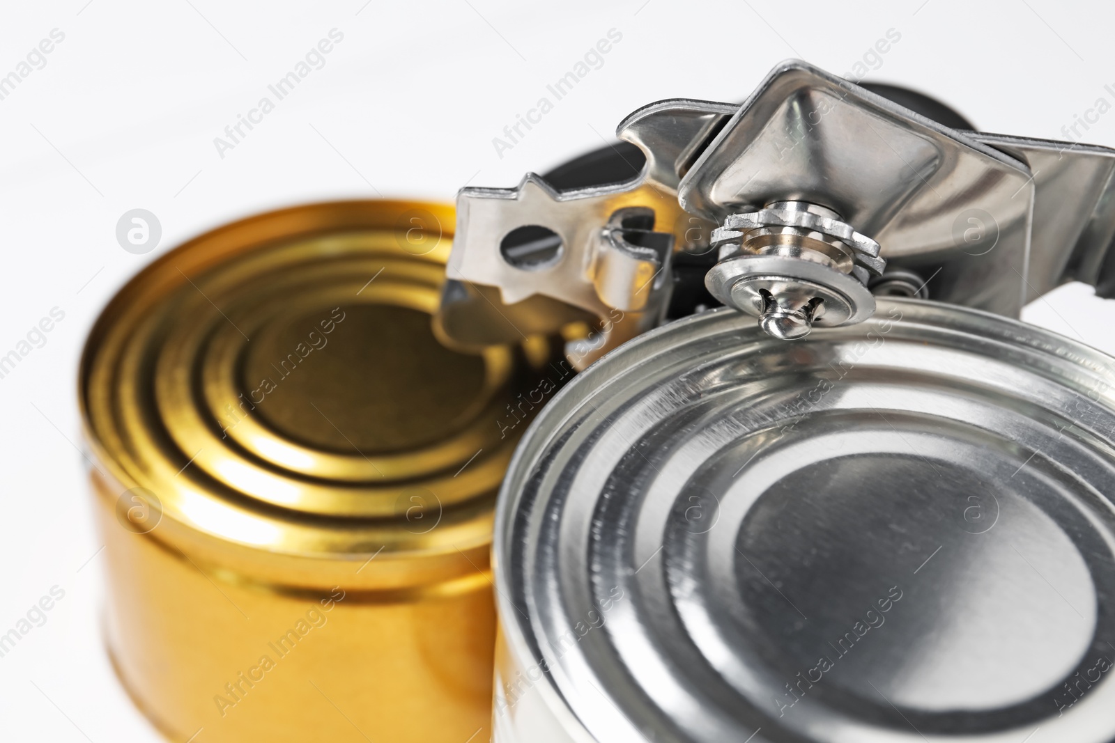 Can opener and tins on white table, closeup Photo of Can opener and tins on white table, closeup