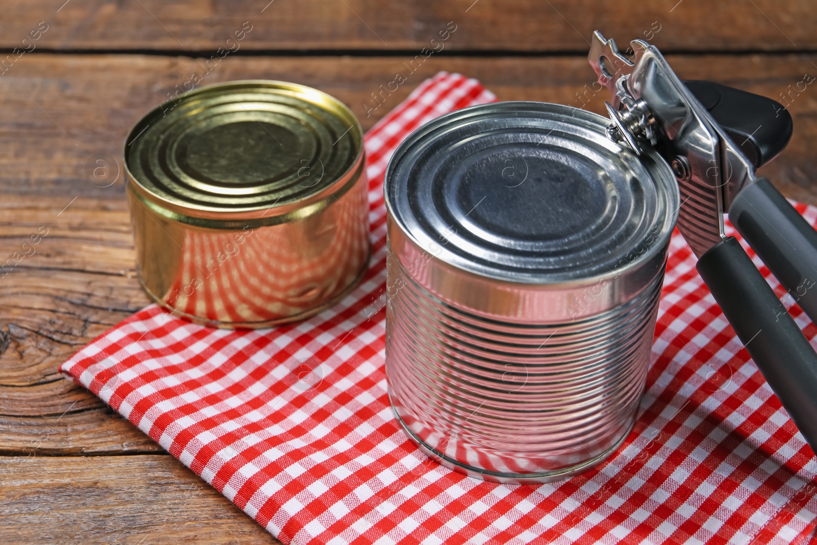 Can opener and tins on wooden table, closeup Photo of Can opener and tins on wooden table, closeup