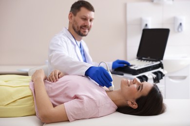 Photo of Sonographer conducting ultrasound examination of woman's thyroid gland in clinic