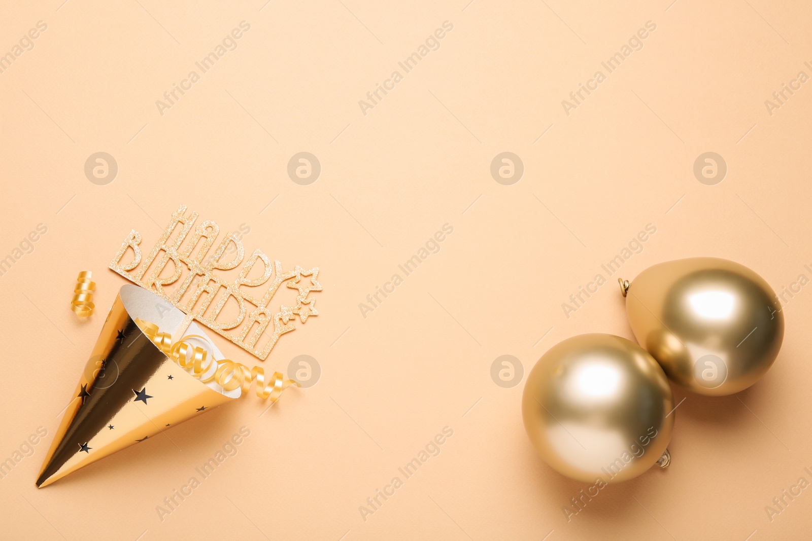 Party hat, topper, streamers and balloons on beige background, flat lay. Space for text Photo of Party hat, topper, streamers and balloons on beige background, flat lay. Space for text