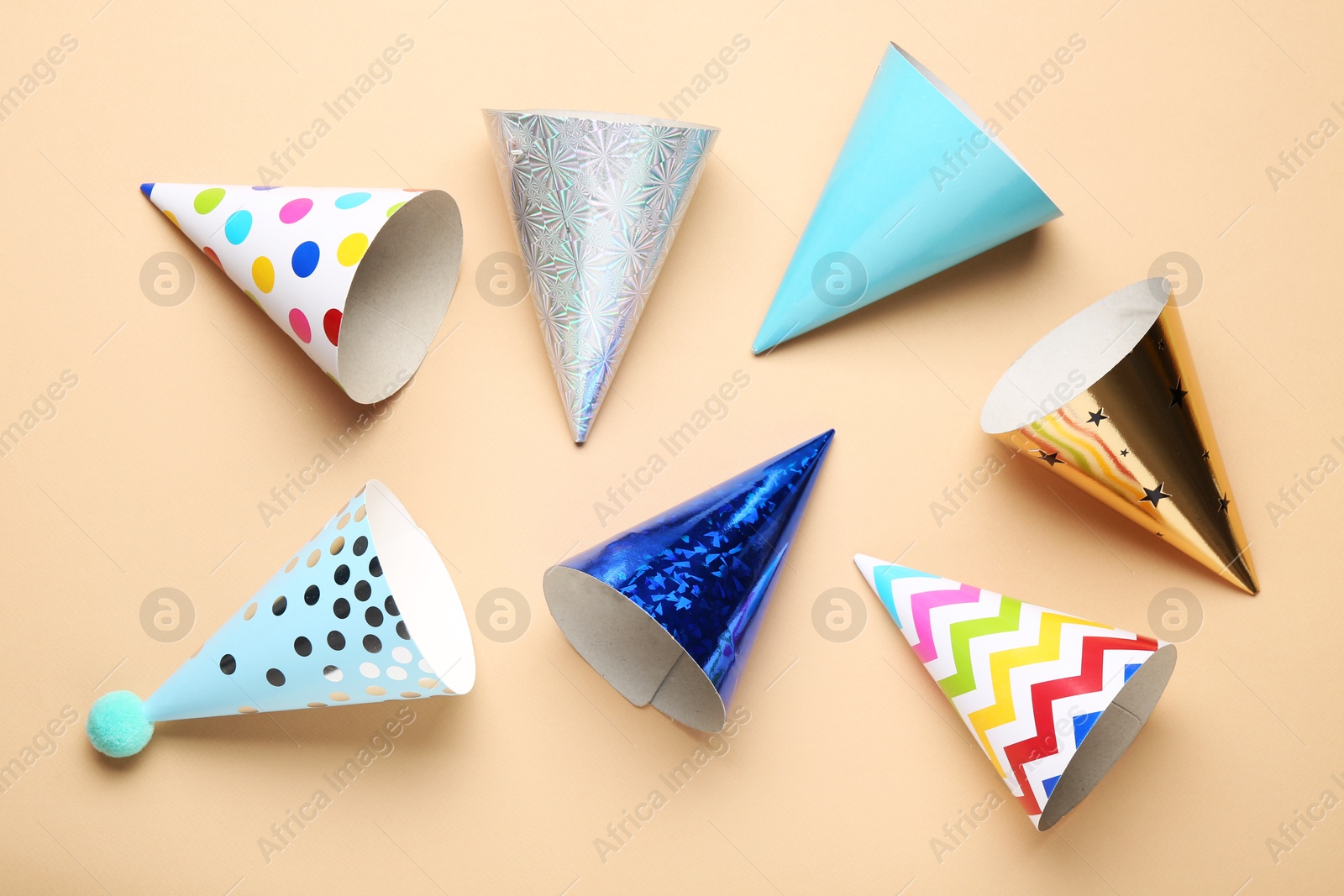 Colorful party hats on beige background, flat lay Photo of Colorful party hats on beige background, flat lay