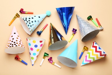 Photo of Colorful party hats and streamers on beige background, flat lay