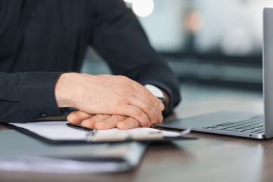 Photo of Man working on laptop at wooden desk in office, closeup