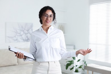 Photo of Professional psychologist with clipboard and pen in office