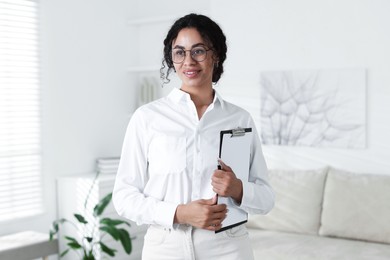 Photo of Professional psychologist with clipboard and pen in office