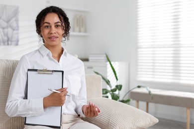 Photo of Professional psychologist with clipboard and pen in office, space for text
