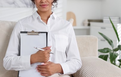 Photo of Professional psychologist with clipboard and pen in office, closeup