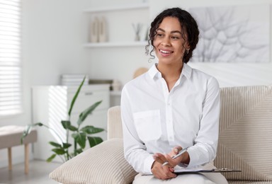 Photo of Professional psychologist with clipboard and pen in office, space for text