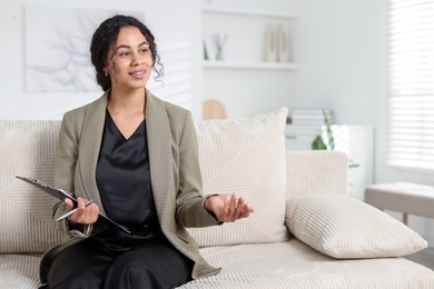 Photo of Professional psychologist with clipboard and pen in office, space for text