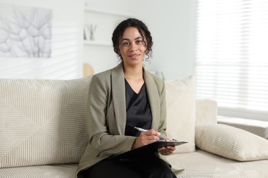 Photo of Professional psychologist with clipboard and pen in office