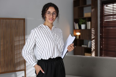 Photo of Professional psychologist with clipboard and pen in office