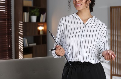Photo of Professional psychologist with clipboard and pen in office, closeup. Space for text