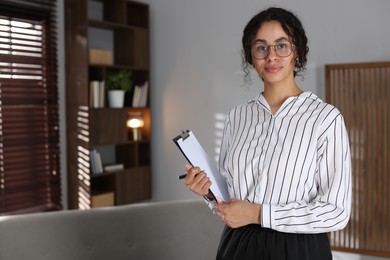 Photo of Professional psychologist with clipboard and pen in office, space for text